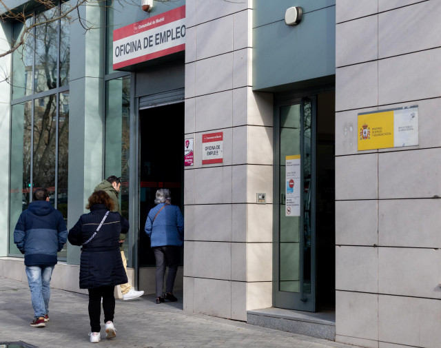 Archivo - Varias personas llegando a una oficina de empleo