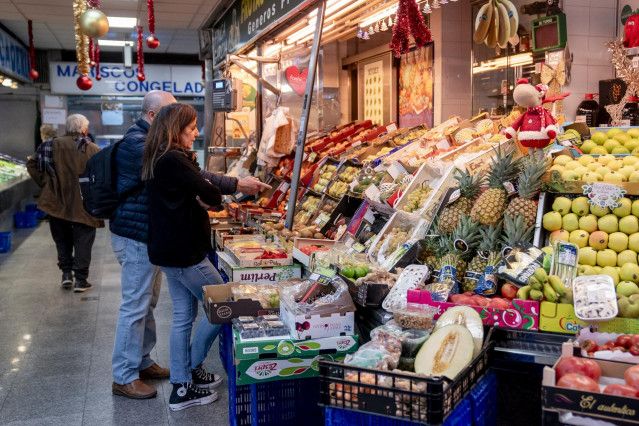 Archivo - Varias personas hacen compras en un mercado