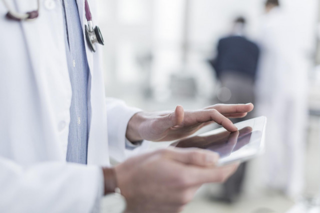 Archivo - Un médico consulta un dispositivo móvil