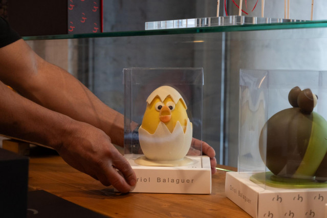 Un hombre coloca una mona de Pascua en un escaparate