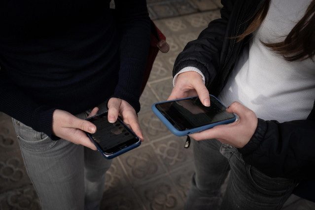 Archivo - Dos personas usan el teléfono móvil, a 1 de febrero de 2024, en Barcelona, Catalunya (España).