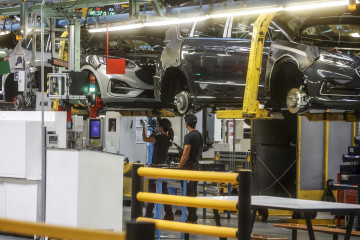 Archivo - Dos trabajadores con un vehículo en una fábrica