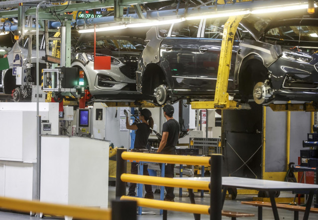 Archivo - Dos trabajadores con un vehículo en una fábrica
