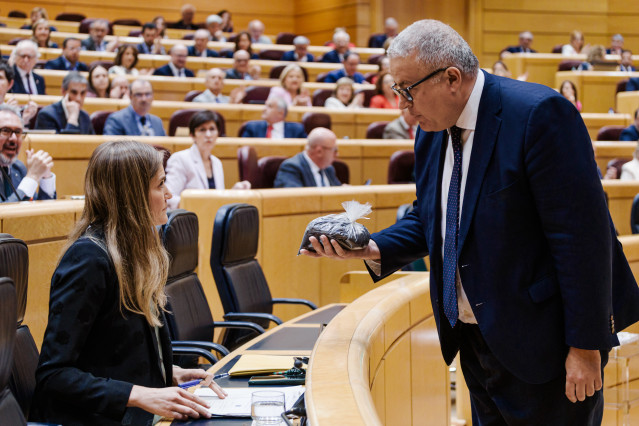 El senador del PP Francisco Bernabé entrega a la vicepresidenta tercera, Sara Aagesen, un saco lleno de estéril minero.