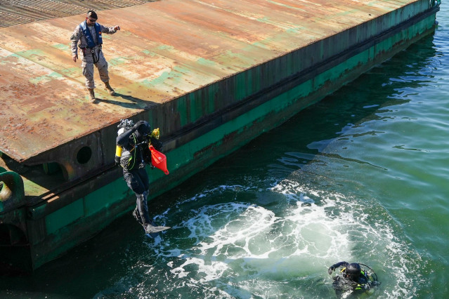 Buzos entran al agua para buscar explisivos en el mar, en un ejercicio cojunto entre la Armada y la Guardia Civil en el Puerto de Huelva.