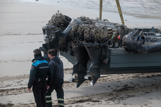 Archivo - Un policía junto a la planeadora varada en la playa de Nemiña, en Muxía. Archivo.