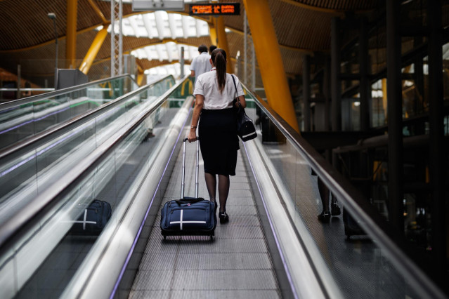 Archivo - Una azafata en las escaleras mecánicas de la Terminal 4 .