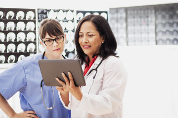 Dos trabajadoras sanitarias revisnado una radiografia en una tablet   Two healthcare workers reviewing an x ray on a tablet