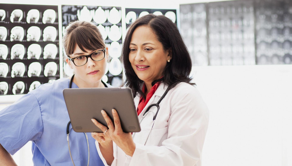 Dos trabajadoras sanitarias revisnado una radiografia en una tablet   Two healthcare workers reviewing an x ray on a tablet