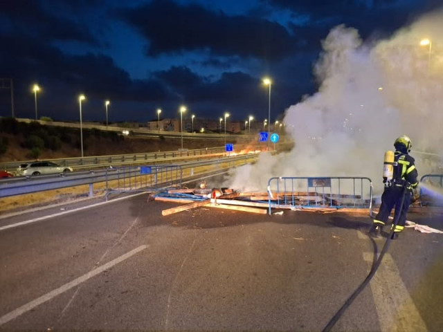 Un bommbero sofoca una barricada en uno de los accesos a Cádiz por la huelga del metal.