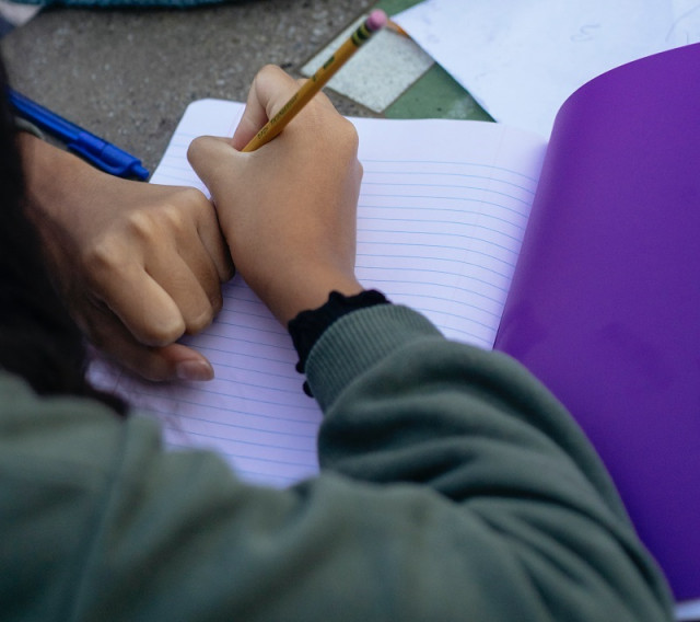 Archivo - Estudiante escribiendo en clase.