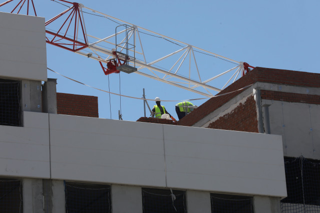 Archivo - Dos obreros trabajan en la construcción de un edificio de viviendas en Madrid