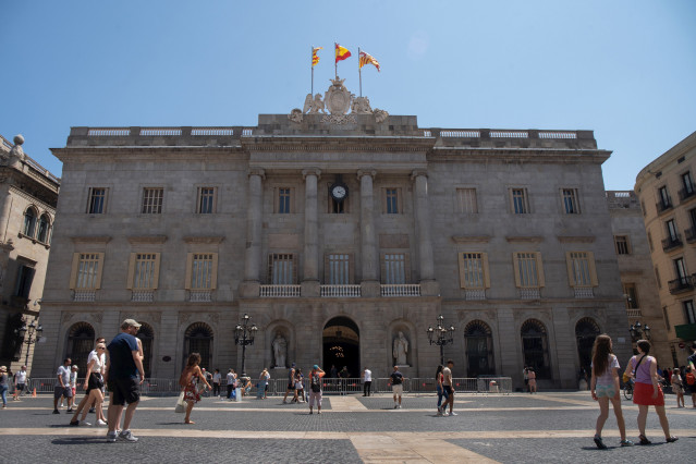 Archivo - Varias personas caminan delante del edificio del Ayuntamiento de Barcelona.