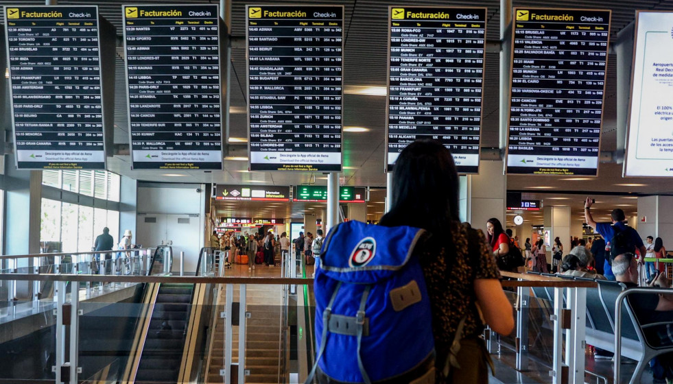 Archivo - Una mujer con una mochila observa los paneles de facturación en el aeropuerto Adolfo Suárez-Madrid Barajas, a 4 de agosto de 2023, en Madrid (España).
