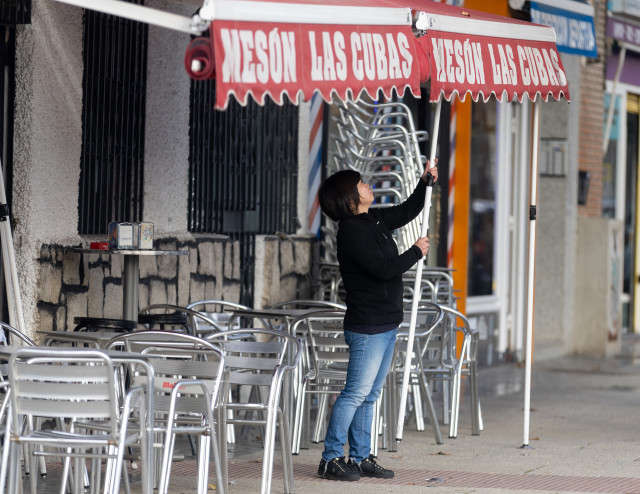 Archivo - Una camarera levanta el toldo de un bar, a 12 de enero de 2024, en Madrid (España).