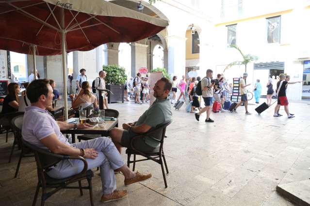 Archivo - Varias personas en una terraza mientras decenas de personas marchan desde la Plaça de la Porta Pintada a la Llotja de Palma para protestar contra el turismo masivo en Mallorca, a 12 de julio de  2024, en Palma de Mallorca, Mallorca, Baleares (Es