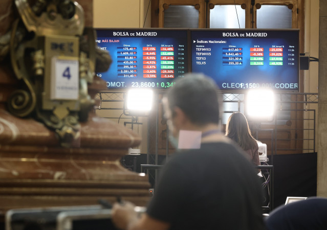 Archivo - Un hombre delante de dos paneles con valores del Ibex 35, en el Palacio de la Bolsa, a 4 de febrero de 2022, en Madrid (España).