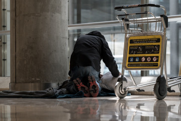 Archivo - Una persona se prepara para pernoctar en la T4 del Aeropuerto Adolfo Suárez-Madrid Barajas