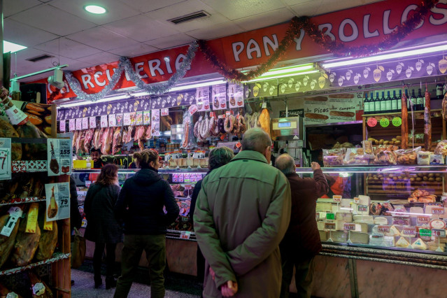 Archivo - Varias personas esperan su turno en la charcutería para realizar sus últimas compras en la tienda de comestibles ‘Los Mares Alimentación’