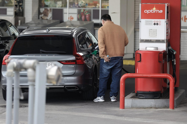 Archivo - Una persona reposta combustible, en un coche, en una gasolinera