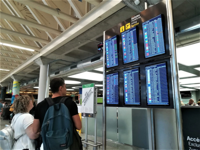Archivo - Turistas comprueban la información de las pantallas de embarque en el aeropuerto de Palma. Recurso