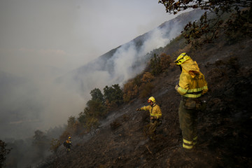 Varios bomberos forestales tratan de extinguir el fuego, a 19 de agosto de 2025, en Palacios de Compludo, León, Castilla y León (España).