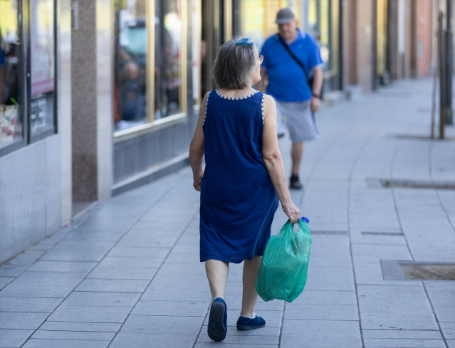 Archivo - Una mujer pensionista caminando por la calle con una bolsa de la compra