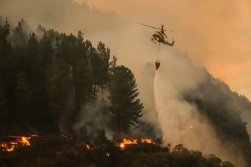 Un helicóptero suelta agua sobre el fuego.