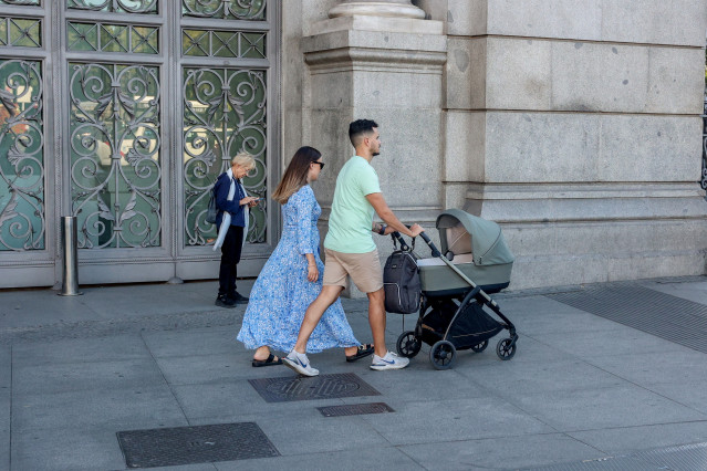 Archivo - Dos personas pasean por Madrid con un carrito de bebé.
