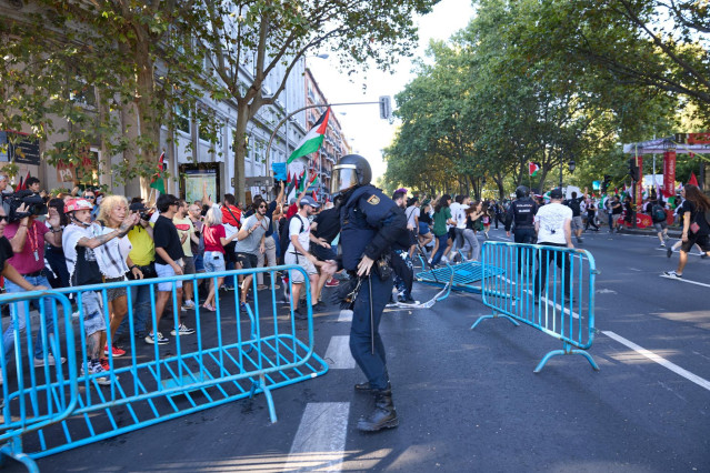 Un agente de Policía Nacional entre vallas tiradas tras cargas policiales a manifestantes que han protestado a favor de Palestina en la última etapa de La Vuelta