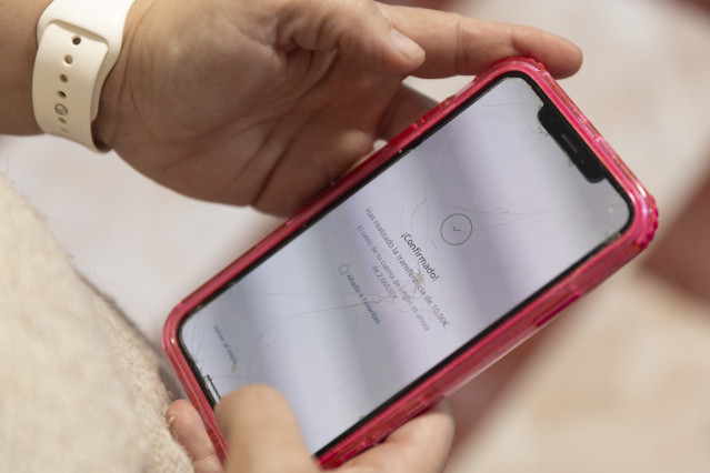 Archivo - Una mujer realiza una transferencia bancaria con su teléfono móvil, a 10 de enero de 2025, en Madrid (España).