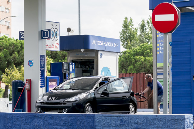 Archivo - Un hombre echa carburante a su vehículo en una estación de servicio