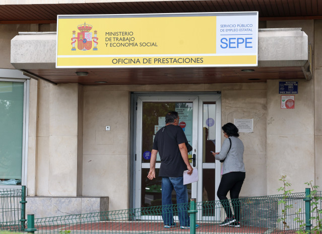 Archivo - Varias personas entrando en una oficina de prestaciones