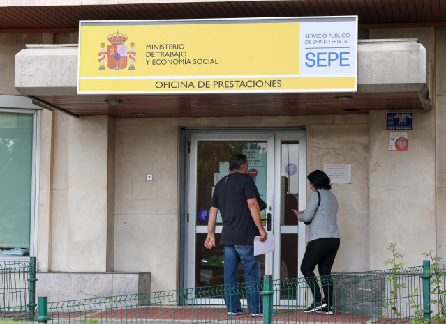 Archivo - Varias personas entrando en una oficina de prestaciones