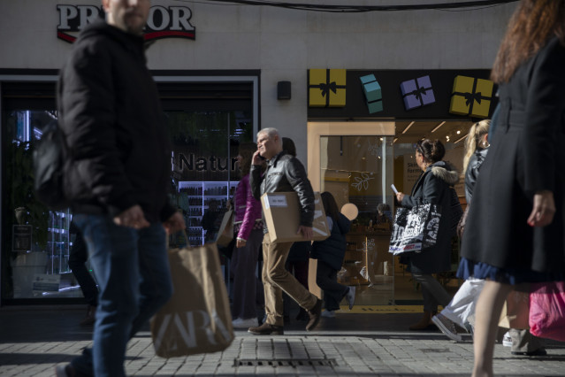 Archivo - Varias personas con bolsas de la compra en una calle céntrica de Sevilla