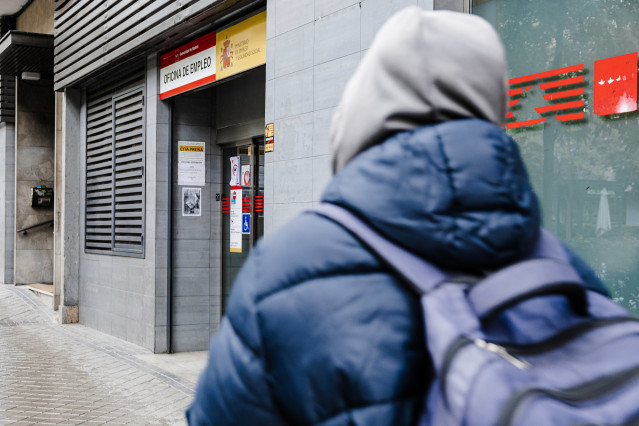Archivo - Un joven pasando por una oficina de empleo
