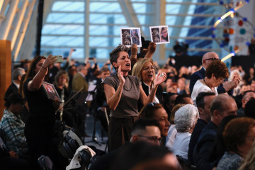 Familiares de víctimas de la dana, con fotos de sus allegados, protestan antes del inicio del funeral de Estado.