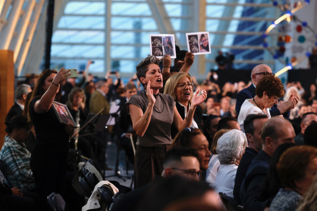 Familiares de víctimas de la dana, con fotos de sus allegados, protestan antes del inicio del funeral de Estado.