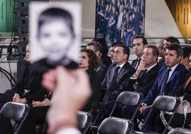 Varios familiares de las víctimas muestran fotos durante el homenaje a las víctimas de la dana