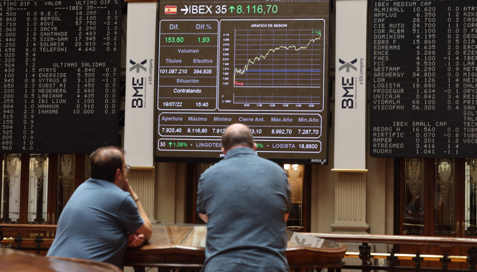 Archivo - Dos personas miran los paneles del Palacio de la Bolsa, a 19 de julio de 2022, en Madrid (España).