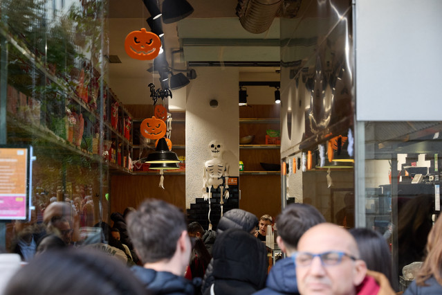 Archivo - Varias personas observan el interior de una tienda en Madrid por Halloween