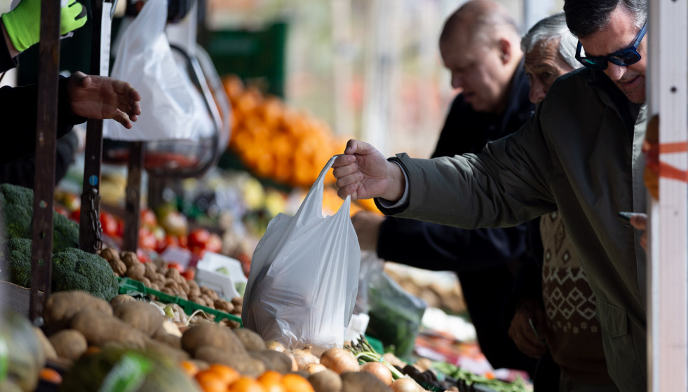 Archivo - Varias personas compran en un mercado de alimentos