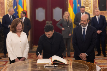 El presidente de Ucrania, Volodimir Zelenski (c), firma el libro de Honor del Congreso, junto a la presidenta del Congreso, Francina Armengol, y con el presidente del Senado, Pedro Rollán (d), en el 