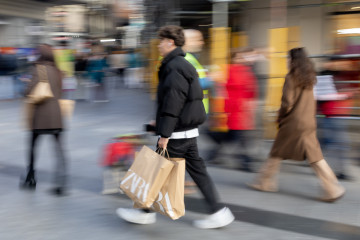 Archivo - Varias personas caminando por la calle tras comprar en tiendas