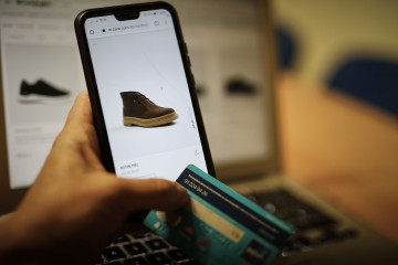 Archivo - Una persona observa en su móvil artículos de moda en la página de un comercio online de moda, en Madrid (España), a 28 de octubre de 2020.