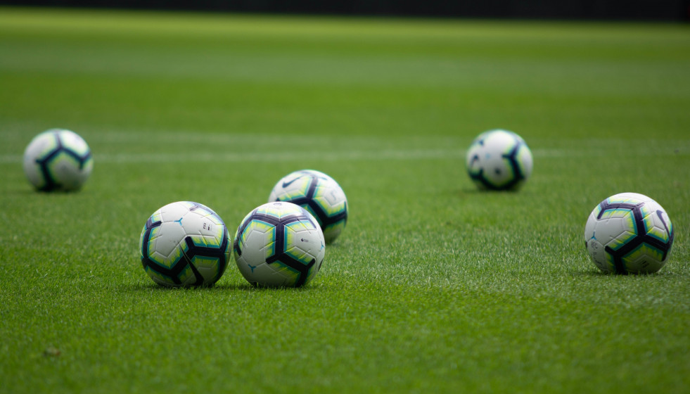 Archivo - Balones de fútbol en un campo