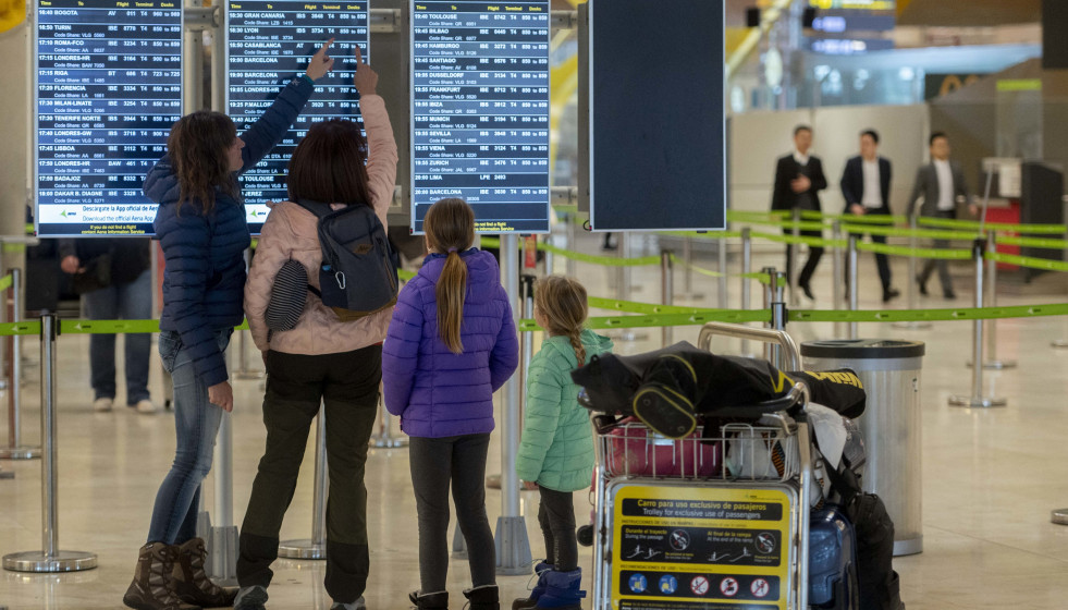 Archivo - Varias personas observan las salidas de los vuelos.