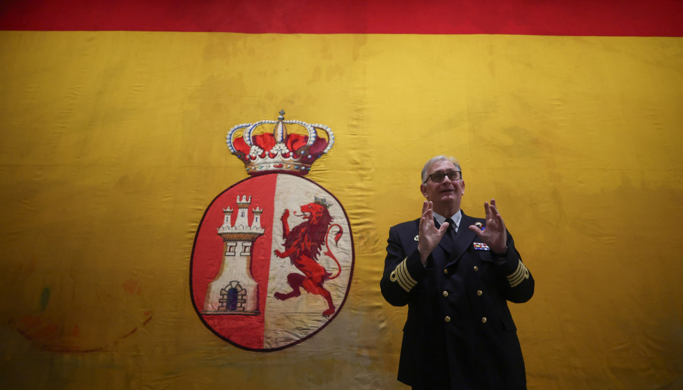 El director del Museo Naval y Capitán de navío, Juan Escrigas Rodríguez, posa delante de la bandera de combate del Crucero Mercedes durante la iInauguración de la exposición temporal ‘La bander