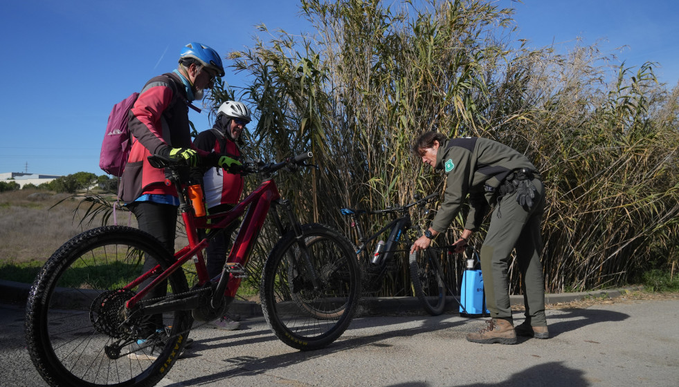Un agente rural de los Mossos d'Esquadra desinfecta las bicicletas de unos ciclistas en las zonas restringidas por la cuarentena ante la peste porcina africana
