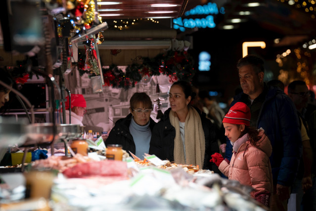Archivo - Varias personas miran el género expuesto, en el Mercado de la Boquería, a 14 de diciembre de 2023, en Barcelona, Catalunya (España).